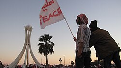 Men standing with a flag that says "PEACE" in Arabic and English days before it was torn down.