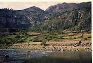 Photograph of a river and its riverbank with mountains in the background