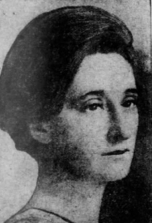 A young white woman with dark hair swept back to nape