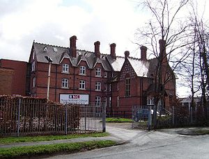 A large brick building with a sign saying "RNC"; a fence and some trees in the foreground.