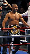 Roy Jones Jr. posing with his champion belt in the boxing ring