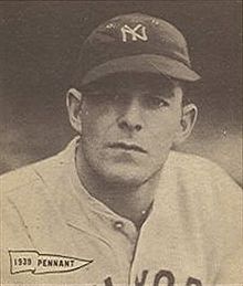 A man in a light baseball jersey and dark cap