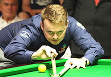 Sean Murphy leaning over a table lining up a shot using a bridge stick