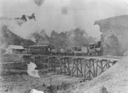 Steam tram crossing Irvinebank bridge over Gibbs Creek ~1911. Locomotive is called Baby and is on a picnic tour to Stannary Hills. (Description supplied with photograph).