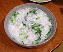 Grains of white rice still hold their shape in brothy porridge mixed with green herbs