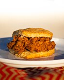 A biscuit cut in half with a deep-fried chicken breast placed inside.