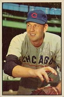 A man wearing a blue cap with a red "C" on the front and a white baseball jersey with "Chicago" written on the chest posing after throwing a ball.
