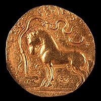 Samudragupta coin with Ashvamedha horse standing in front of a yūpa sacrificial post, with legend "The King of Kings, who had performed the Ashvamedha sacrifice, wins heaven after conquering the earth".[106][107]