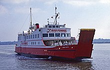 Three-quarter view of ship, with red hull and white superstructure, steaming left to right