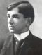 A black-and-white photograph of a young man in a suit with a tie