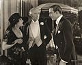 Theodora Fitzgerald and her father Captain Fitzgerald (played by Gloria Swanson and Alec B. Francis) talk to Lord Hector Bracondale (Rudolf Valentino) in Beyond the Rocks