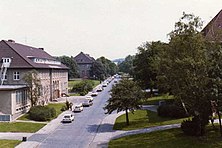 A photograph of a street and buildings inside Barker Barracks c1980. Taken from a high vantage point in the main HQ building it is looking eastwards.[3]