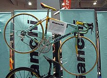 A turquoise and yellow Bianchi bicycle hung up at a cycle show stand