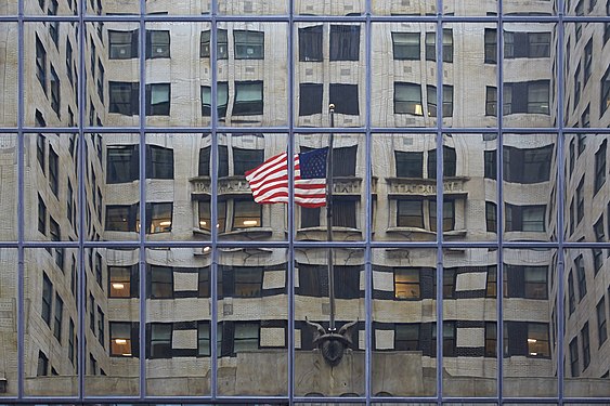Chrysler Building view on opposite building on 42nd street, mirrored flag and central south facade of Chrysler Building