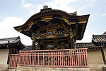 Black wooden gate with colorful ornamentation and a Chinese style gable on the front.