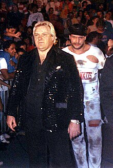 Bobby Heenan, dressed in a black sequin jacket, leads The Brooklyn Brawler to the ring in 1989