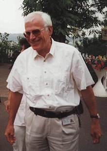 picture of a smiling man with white hair, wearing dark glasses