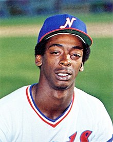 A man in a white baseball jersey and a blue cap with a white "N" on the front smiles for the camera.