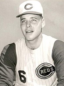 A man in a light baseball uniform with dark sleeves and a light cap with a "C" on the center