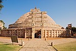 A large stupa in stone with an elaborate gate in front