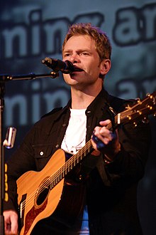 Chapman performs a song while playing an acoustic guitar