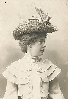 Black and white half-length photo of a woman wearing a straw hat, head in profile looking right