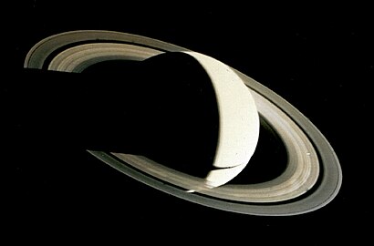 View of Saturn lit from the right. Saturn's globe casts its shadow over the rings to the left. Part of the lower hemisphere can be seen through the rings. Some of the spoke-like ring features are visible as bright patches.