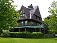 A stone mansion surrounded by grass and bushes