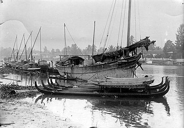 Ship from Madura along the banks of the Martapura River in Banjarmasin, South Borneo, where (in the foreground) also typical Banjarese gondola-shaped prahus (jukung tambangan) are situated.