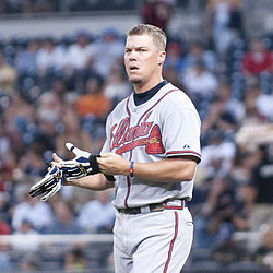 Chipper Jones, wearing an Atlanta Braves uniform, taking off his batting gloves