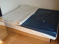 A bed with comforter pulled forward to show the water mattress