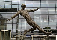 A bronze sculpture of a footballer mid-kick