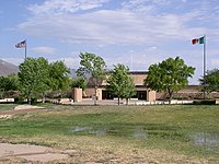 Short building with Mexican and American flags flying