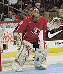 Woman wearing red hockey uniform and face mask