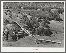 Irrigation water crosses a ditch in a hollowed out log called a canoa. 1930s photo.