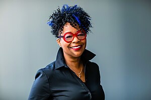 Janeen Uzzell wearing red glasses looking towards the camera.