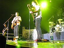 Several man performing onstage playing and singing into a microphone