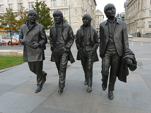 statue of four musicians in 1960s attire walking in the street