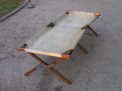 A mid-20-century folding camp bed, wood, cotton duck, and metal