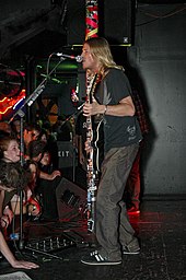 Man performing to an audience with both a guitar and a microphone