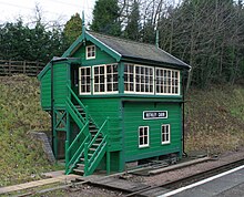 Green trackside building with stairs