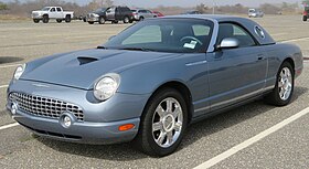 Blue sports car with circular headlights and seven-spoke silver wheels.