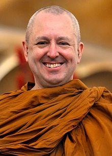 Ajahn Brahm wearing saffron robes, grinning at camera