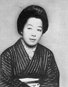 A Japanese woman, wearing a striped kimono, hair in a bouffant arrangement