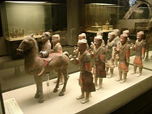 A photograph of teracotta warriors held at a glass exhibit in a museum