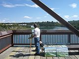 Artist working en plein air, on a pedstrian bridge in Edmonton.