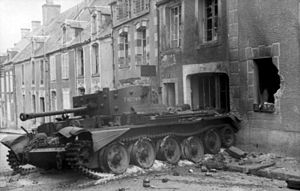 一輛陷在礫石中的坦克位於一處燒毀的房舍前,它跨在馬路與人行道上.