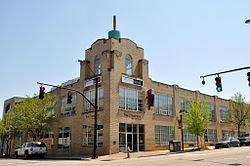 Two-storey brick building with large windows and an additional third-storey for a small section of the corner above the entrance