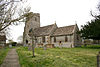 Stone building with prominent square tower. In the foreground are gravestones.