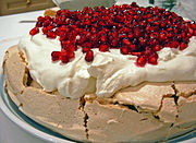 A pavlova garnished with pomegranates and cream